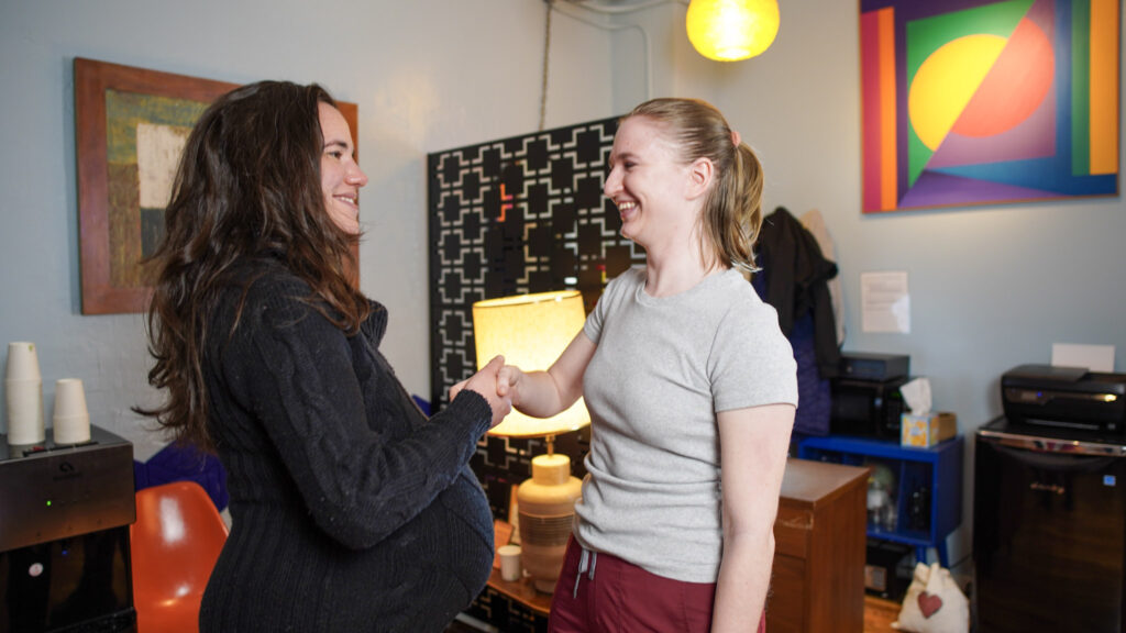 Massage therapist greeting a client with a friendly handshake in the Bodyworks DW waiting area, symbolizing mutual respect and clear agreements.