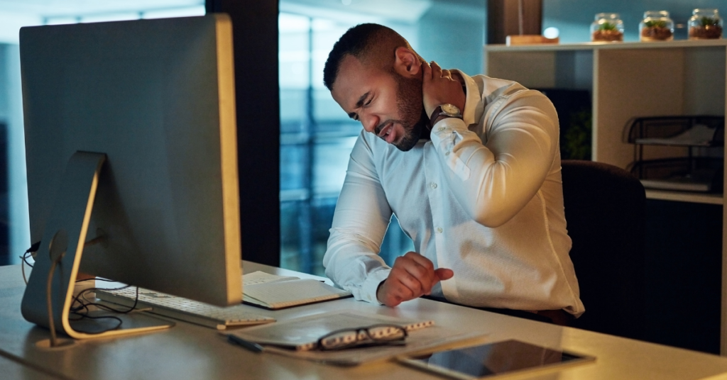 Person experiencing neck pain at desk.